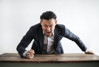 Conflicten beschrijven: een boze man die met zijn vuist op tafel slaat.